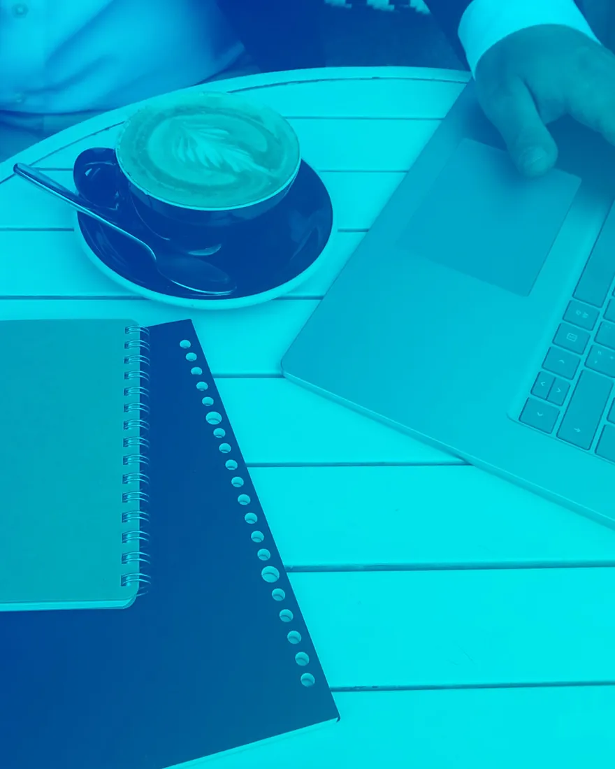 Blue duotone: notebook, coffee and laptop on a work table